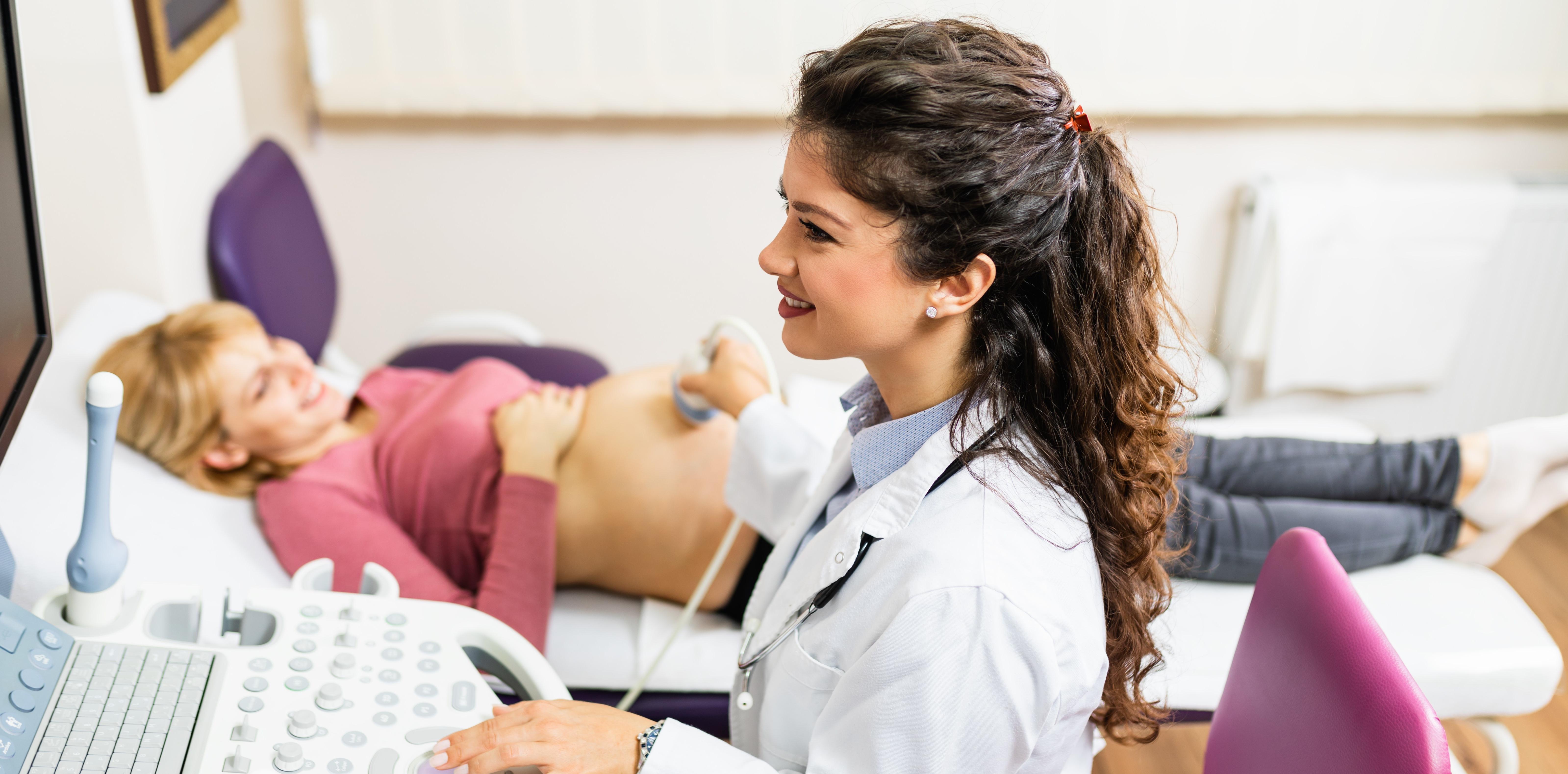 Obstetrician examining pregnant belly by ultrasonic scan.